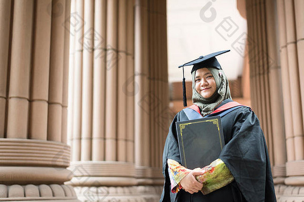 教育理念——年轻的马来西亚女孩在毕业典礼上微笑着持有学位证书