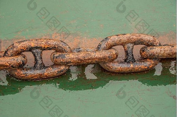 中国丰都——2010年5月8日：湿绿色金属表面上5件重棕红色生锈金属链环的特写。