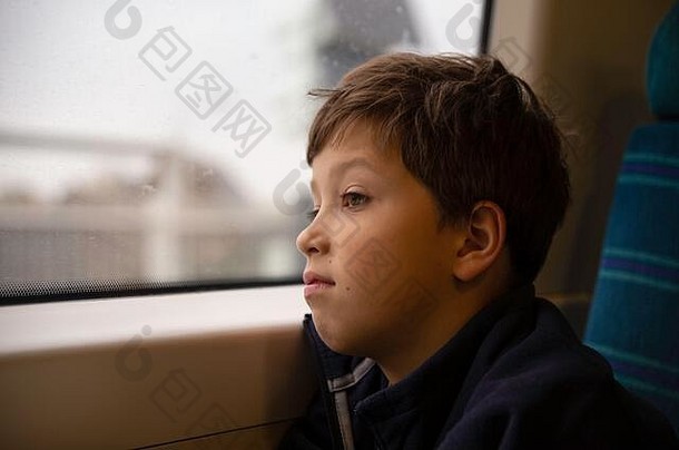 沉思的男孩思考着，看着<strong>火车</strong>窗玻璃后面的风景。