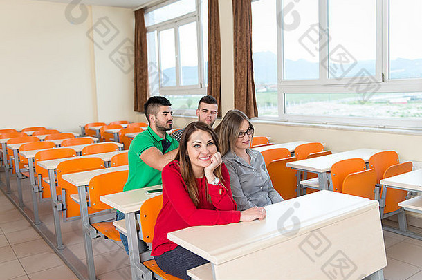 一群年轻漂亮的青少年学生坐在一张桌子旁，在大学教室里学习功课