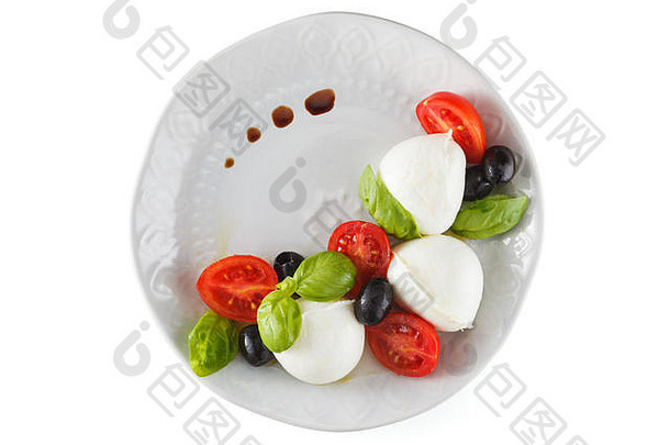 马苏里拉，西红柿和罗勒放在盘子里。在蓝色的乡村桌子上。