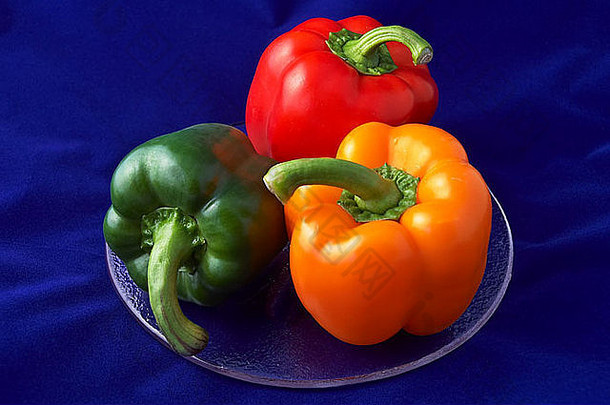 玻璃盘上以三个一组的形式展示的一种绿橙色和红辣椒