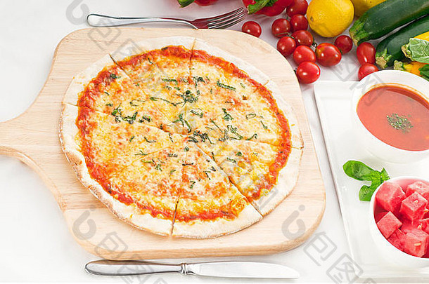 意大利原汁薄皮玛格丽特比萨，旁边有加兹帕乔汤和西瓜，背景是蔬菜
