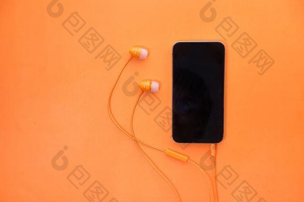 橙色背景上的智能手机和耳机。