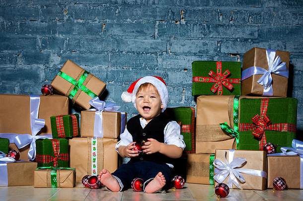 戴着圣诞帽，穿着西装，面带微笑的小圣诞老人。新年快乐，圣诞快乐。给孩子们的节日和礼物。