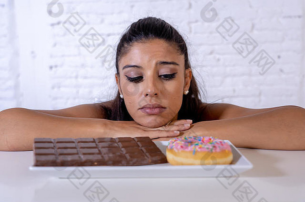 饥饿美丽的年轻女子不快乐地渴望甜巧克力和甜甜圈，不能在节食中进食减肥糖瘾糖尿病和不健康