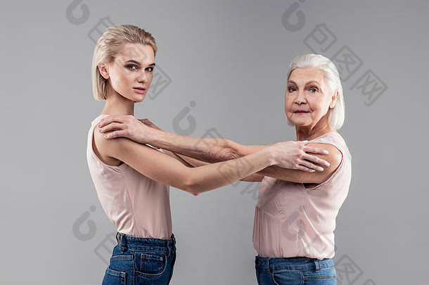 金发迷人的女人和灰头发的老太太互相抚摸着肩膀