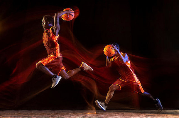 获胜的两个步骤。在黑暗的演播室背景下，红队的非洲裔美国年轻篮球运动员正在比赛，霓虹灯闪烁。运动、运动、活力和健康生活方式的概念。