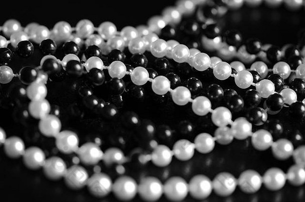 黑色和白色串珠项链，背景为深色，特写。非黑即白的