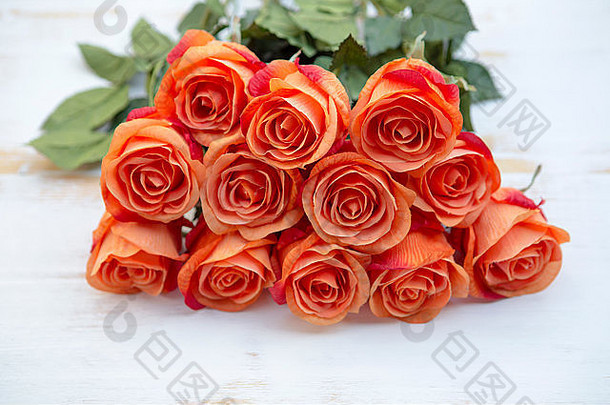 白色复古木背景上点缀着一束美丽的橙玫瑰
