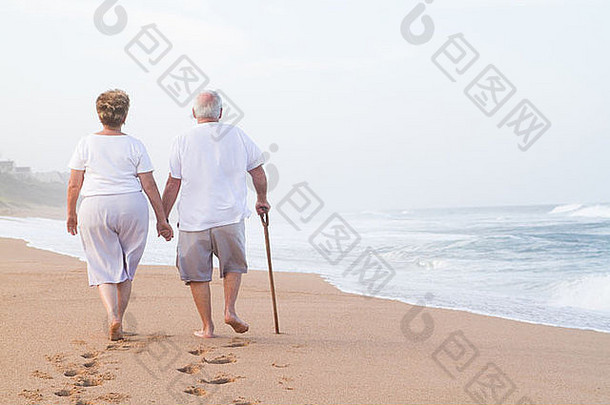 老年夫妇手牵手在沙滩上散步