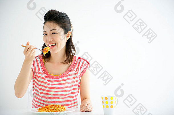 日本，大阪府，年轻女子在吃意大利面，微笑着