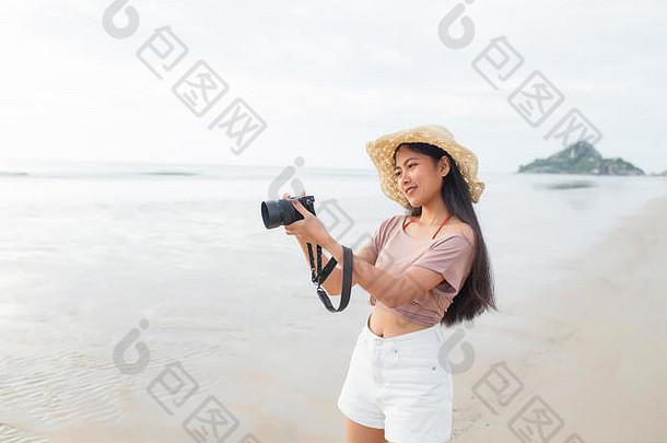美丽的年轻亚洲女子在热带海滩拍照