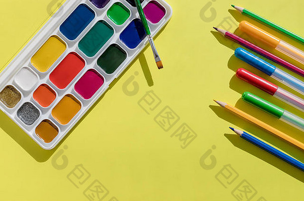 学校用品。一套新的水彩画、画笔和毛笔、马克笔和铅笔位于浅黄色背景上。艺术和绘画工具。平铺。拷贝空间
