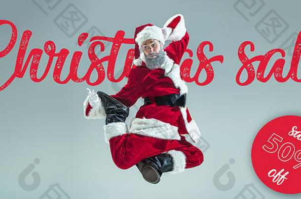 灰色工作室背景上的圣诞老人快乐。穿着传统节日服装的白人男模特。节日的概念，新年，冬天的心情，礼物。圣诞节大减价。空间。