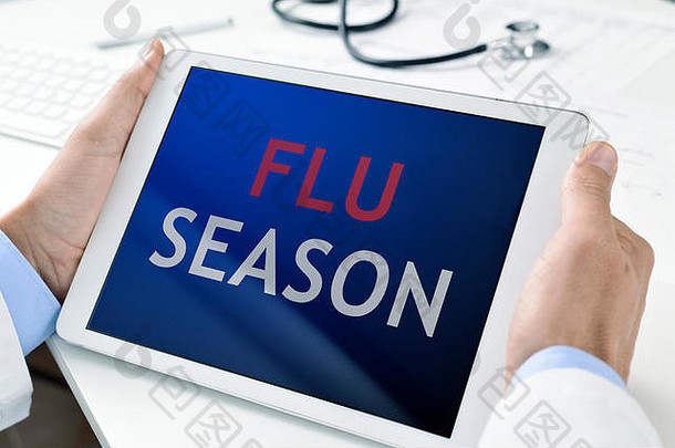 一名白人医生手持平板电脑，屏幕上写着“流感季节”的特写镜头