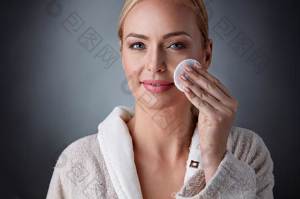 快乐中年妇女用化妆棉洗脸<strong>卸妆</strong>，美容、美容、护肤理念