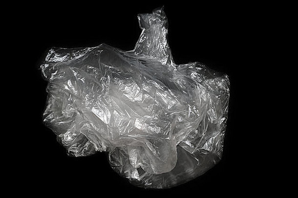 一个塑料袋隔离在黑色背景上。不回收，造成环境污染。污染概念。逐步淘汰塑料袋。