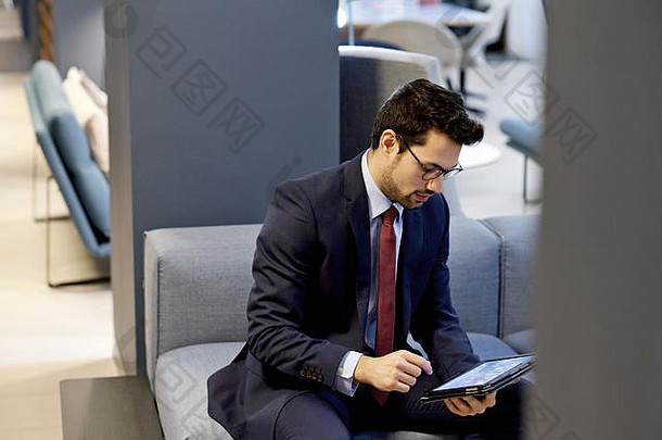 拉丁美洲人商人穿着聪明的西装持有移动平板电脑设备当代室内设计办公室
