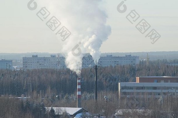 在多云的天空背景下，浓烟从室内烟囱升起。俄罗斯城市的工业区。有建筑物和公园的冬季城市景观。库存照片，文本空白。