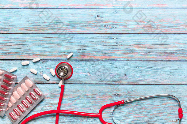 世界卫生日医疗保健和医疗概念蓝色木质背景上的红色听诊器和药物