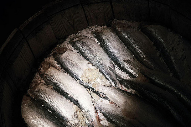 深色背景下木桶中腌制鲱鱼的特写照片