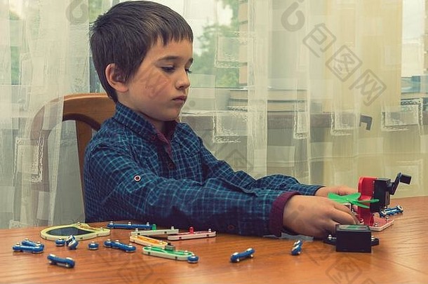 那男孩在玩<strong>电动玩具</strong>。这孩子是由智力<strong>玩具</strong>玩的。一个穿蓝色衬衫的男孩精通电子技术。早期教育的概念