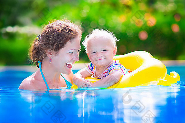 快乐的家庭，年轻活泼的母亲和可爱的小卷发宝宝在游泳池里玩耍，孩子们学习游泳