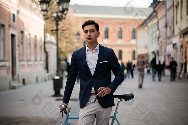 优雅的年轻的男人。蓝色的<strong>自行车</strong>在户外街