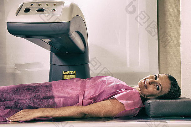 一名40多岁的妇女正在骨密度计机器上接受扫描。
