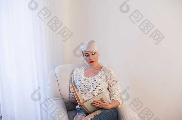 在白色房间的椅子上看书的女人