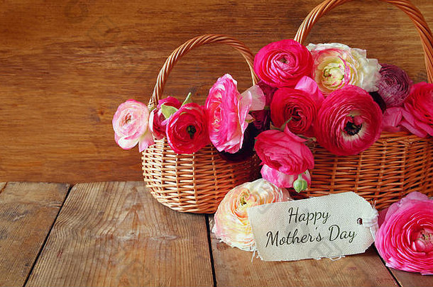 粉红色的花在木桌上卡片旁边的篮子里。母亲节快乐。