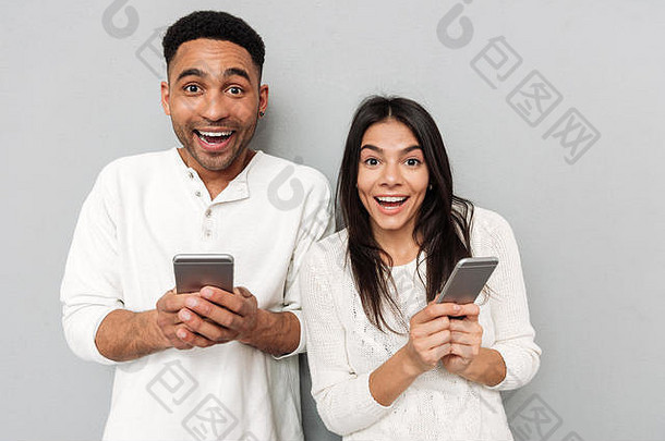 照片年轻的快乐爱的夫妇摆姿势灰色墙相机聊天移动手机