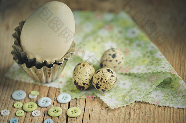 不同的鹌鹑蛋和鸭蛋放在桌子上，有纽扣和小金属烤制形式