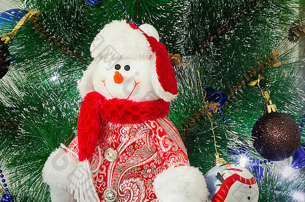 戴着红帽子和优雅衣服的雪人在<strong>装饰</strong>过的圣诞枞树上