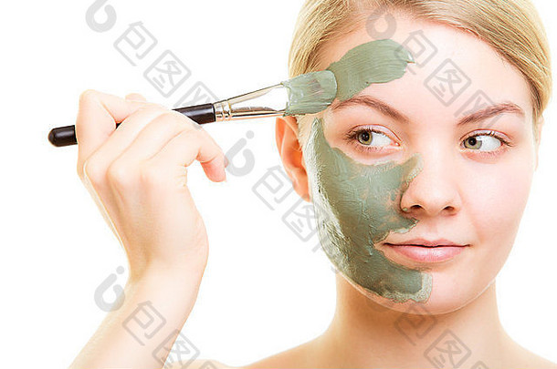 皮肤护理女人应用刷粘土泥面具脸孤立的女孩采取护理干肤色美治疗