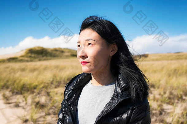 马萨诸塞州特鲁罗市科德角国家海滨，一位中国妇女在阳光明媚、多风的日子里，在户外沉思。