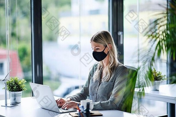 年轻的女人脸面具回来工作办公室封锁移动PC