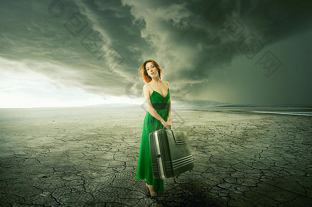 美丽的女人绿色衣服手提箱站中间沙漠山背景