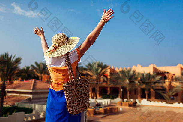 快乐的老妇人走在酒店的地盘上，举手致意。在埃及的暑假。时尚外观