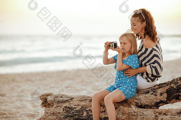 快乐时尚的妈妈。女儿旅行者坐着木障碍采取<strong>照片</strong>复古的<strong>照片</strong>相机海滩晚上