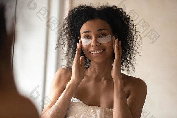 有吸引力的非洲女人应用黑眼圈补丁镜子
