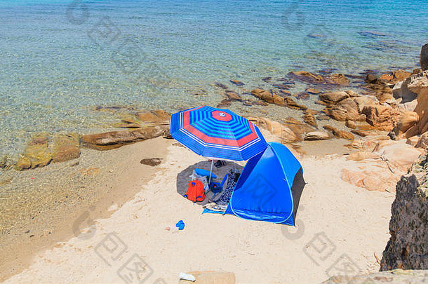 夏季旅行在孤独的沙滩上露营。蓝色沙滩帐篷和遮阳伞