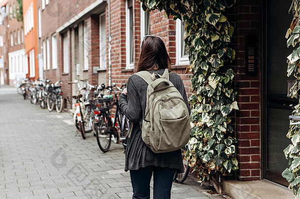 背着背包的游客正在一个陌生的城市寻找网上预定的住宿。或者一个背着背包的女学生正在城市里散步。