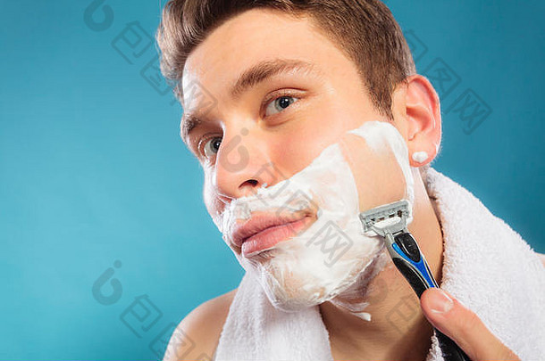 年轻人用奶油泡沫剃须刀刮胡子。帅哥去胡子。皮肤护理和卫生。