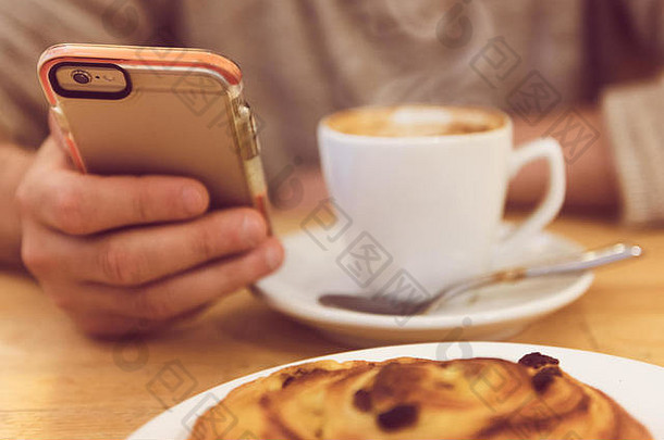 总是保持联系。无法辨认的男子在餐厅吃早餐时喝咖啡和手持智能手机的详细图像。