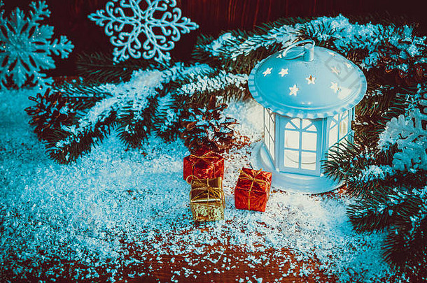 圣诞灯由蜡烛、圣诞树枝、礼物、圆锥体、雪花和雪在复古木背景上点亮。自由空间