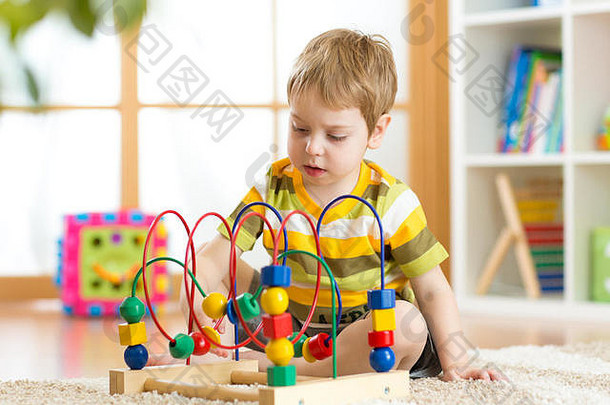 小男孩在托儿所玩一个五颜六色的逻辑玩具