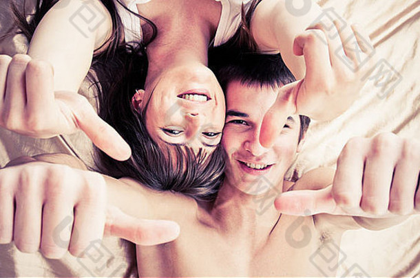 一对幸福的夫妇竖起大拇指躺在床上