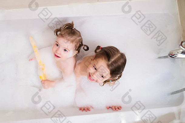 两个小女孩在浴缸里用泡泡洗澡
